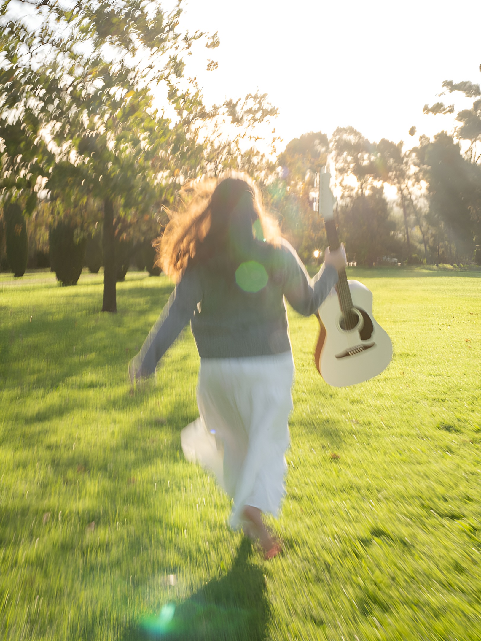 Ellise Hill running through a sunlit field with a guitar